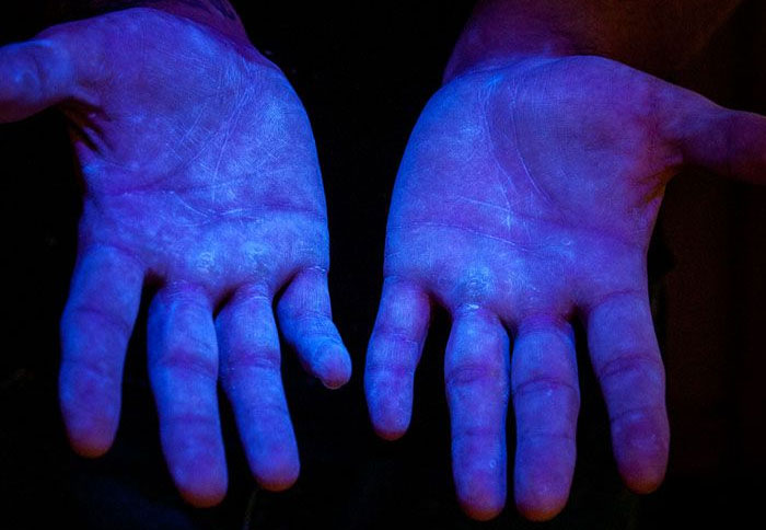 Foto 6. Material fluorescente bajo la luz ultravioleta (UV) para demostrar que el producto cubre la totalidad de las manos. Fuente www.glogerm.com