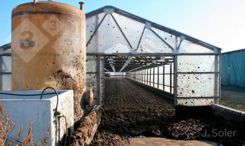 Figura 2. Imagen de sistema de secado solar mediante invernadero. En primer plano se aprecia el dep&oacute;sito de &aacute;cido y un biofiltro para el tratamiento de las emisiones gaseosas (gentileza de J. Soler, EMA depuraci&oacute;, Olot, Gerona).
