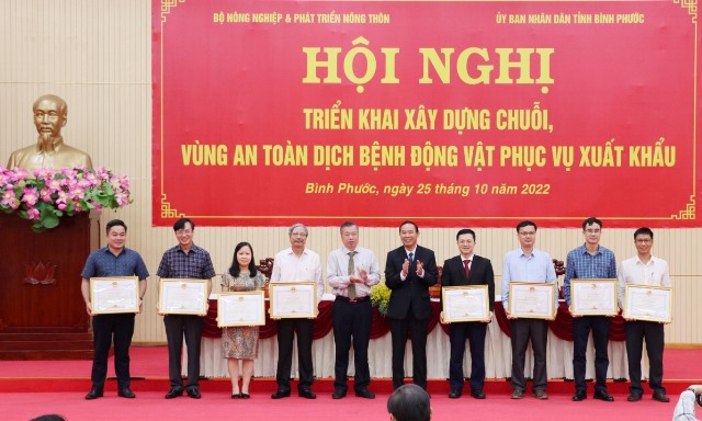 Thứ trưởng Phùng Đức Tiến và PCT UBND tỉnh Bình Phước Huỳnh Anh Minh trao Bằng khen của CT UBND tỉnh Bình Phước cho các tập thể, cá nhân có nhiều thành tích trong kiểm soát dịch bệnh, xây dựng chuỗi, vùng an toàn dịch bệnh động vật phục vụ xuất khẩu